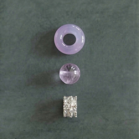 AETHER Key: AWARENESS lavender amethyst bracelet deconstructed detail shot, featuring one icy chalcedony running ring (donut shape), one translucent lavender amethyst bead, and one brilliant silver-set pavé spacer, macro perspective on a muted grey-green background.