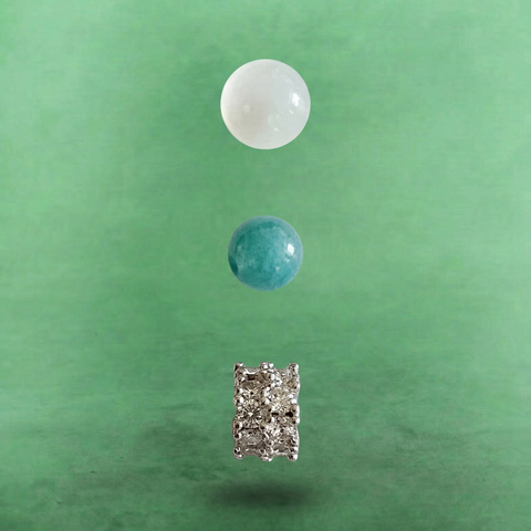 Macro detail of AETHER Key: INTUITION, showing a glowing white moonstone bead, a smooth green Burmese jadeite bead, and a brilliant silver pavé spacer.