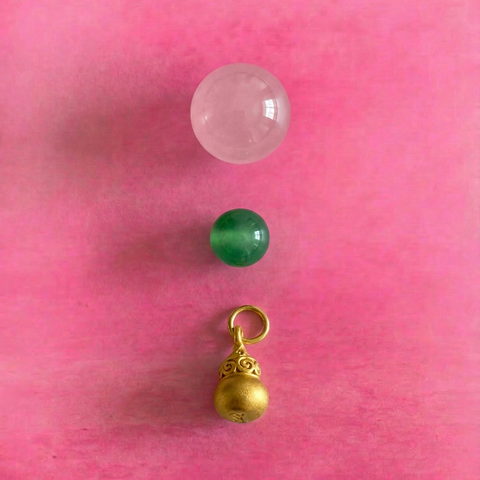 Macro detail of AETHER Key: RESONANCE, showing a translucent pink rose quartz bead, a vivid green agate bead, and a detailed gold Wu Lou charm.