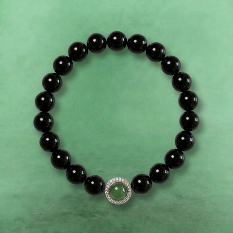 AETHER Key: PROTECT obsidian bracelet, minimalist deep black beads, featuring a central faceted green crystal surrounded by sparkling diamond-like halo, dark translucent aesthetic, grounding spiritual jewelry.