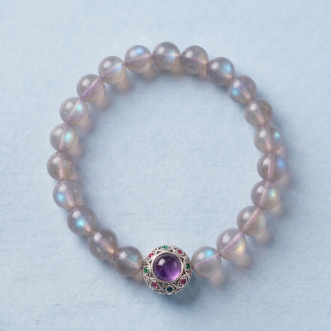 AETHER Intuition Collection - Natural Labradorite crystal bracelet with an intricate silver and amethyst center bead, resting on a soft blue background.